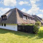 Haus mit strohgedecktem Dach und weißer Fassade im Garten