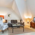 Wohnzimmer mit Sofa, Sessel, Couchtisch und Fernseher auf Holzschrank.