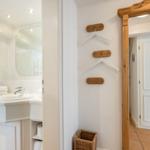 Badezimmer mit Waschbecken und Spiegel. Wand mit Haken und Korb.