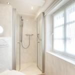 Badezimmer mit Dusche, Fenster und Toilette