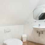 Badezimmer mit Toilette, Waschbecken und Spiegel an der Wand.
