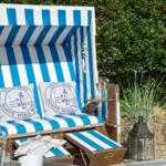 Blau-weiße Strandliege mit Kissen und Getränken im Garten.