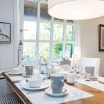 Esstisch mit Tassen, Gläsern und Dekoration an Fenster