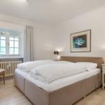 Schlafzimmer mit Bett, Nachttisch und Fenster.