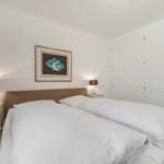 Schlafzimmer mit Doppelbett, Nachttischen und weißen Schränken.