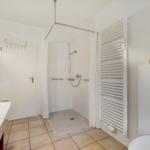 Badezimmer mit Dusche, Waschbecken und Heizkörper
