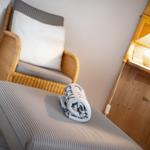 Rattan-Stuhl mit Kissen und gestreifter Auflage. Holzschrank mit Lampe und Handtuch.