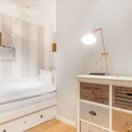 Schlafzimmer mit Bett, Schrank und Stehlampe.