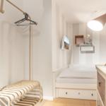 Schlafzimmer mit Bett, Kleiderständer und Schreibtisch