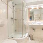 Badezimmer mit Dusche, Waschbecken und Spiegel.