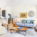 Wohnzimmer mit Sofa, Kamin und Essbereich. Holztisch, Sessel und Wanddekoration.