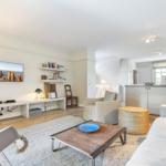 Wohnzimmer mit Sofa, Couchtisch und Fernseher an der Wand.