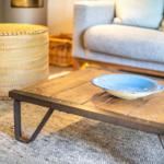 Holztisch mit blauer Schale, Sofa und Korb im Wohnbereich.