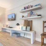 Wohnraum mit Schreibtisch, Bücherregal und Fernseher an der Wand.