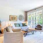 Wohnzimmer mit Sofa, Kamin und Glastür zum Garten