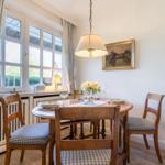 Dining room with wooden table, four chairs, and garden view.