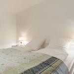Bedroom with bed, two nightstands and lamps. A round mirror hangs on the wall.