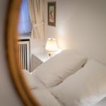 Bedroom with bed, nightstand, and lamp. Window with curtains and wall art.