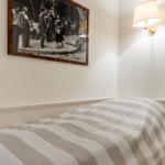 A bed with striped bedding, wall art, and wall lamp.