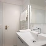 Bathroom with washing machine, mirror, and towel rack.