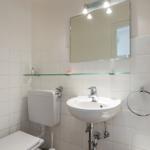 Bathroom with toilet, sink, and mirror.