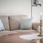 A sofa with cushions, a floor lamp, and a table lamp with a candle.