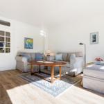 Living room with sofa, table, and rug. Windows and door are visible.