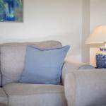 Gray sofa with blue pillow and lamp with blue-white pattern.