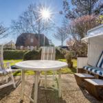 Terrace with table, chairs, and beach cabana under sun.