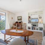 Living room with dining table, TV, and view to balcony.