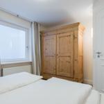 Bedroom with bed, wooden wardrobe, and window with curtains.