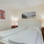 Bedroom with bed, two nightstands, and wall pictures.