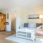 Living room with sofa, wicker chair, and wooden wardrobe. Wall art with sailboats.