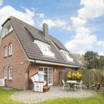 House with garden, terrace, and beach chair. White windows and brick wall.