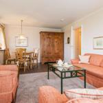 Wohnzimmer mit Sofa, Couchtisch und Essbereich. Holzmöbel und Bilder an den Wänden.