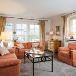 Wohnzimmer mit zwei orangefarbenen Sofas, Glas-Tisch und Holzmöbel.