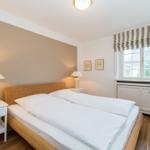 Schlafzimmer mit Doppelbett, Nachttischen und Fenster mit Markise.
