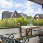 Terrasse mit Tisch, Stühlen und Blick auf Häuser und Bäume.