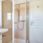 Badezimmer mit Dusche, Waschbecken und Spiegel.
