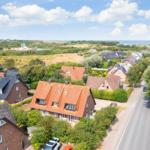 Dorf mit Häusern, Grünflächen und Blick aufs Meer.