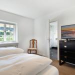 Bedroom with double bed, TV, and view of garden.