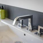 Sink with modern faucet and green bottles.