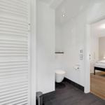 Bathroom with toilet and shower. View into the bedroom with bed.