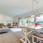 Dining area with table and chairs next to a living room with sofa and TV.