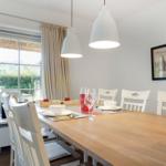 Dining table with chairs, windows, and pendant lamps