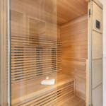 Sauna with wooden walls and bench, door with glass and wooden frame