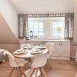 Dining room with table, chairs, and windows. Adjacent room with sofa and bed.