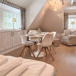 Open living and dining area with sleeping space. Wooden floor, windows, and furniture.