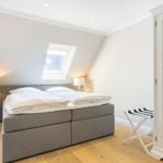 Bedroom with double bed, sloped ceiling, skylight, and wooden floor.