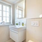 Bathroom with sink, mirror, and window. A bowl with stones sits on the windowsill.